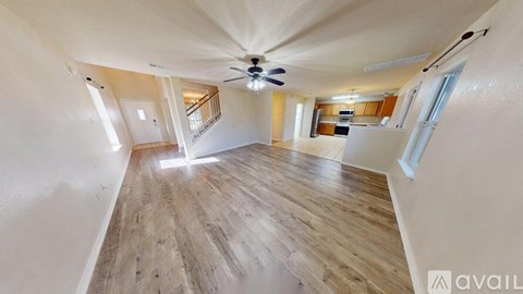 A spacious room with wooden flooring and a ceiling fan.