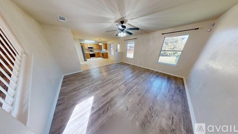 A spacious room with a ceiling fan and wooden flooring.