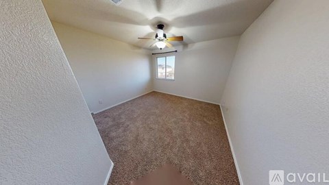 A room with a carpeted floor and a ceiling fan.