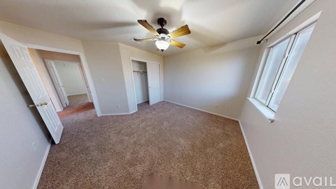 A room with a carpeted floor and a ceiling fan.