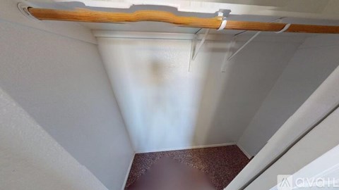 A white wall with a brown floor and a wooden beam.