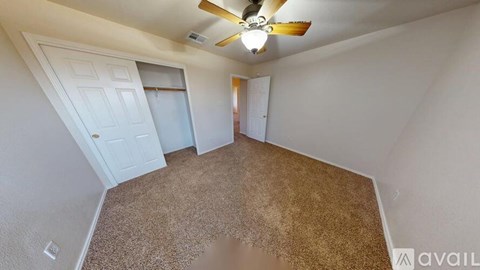 A room with a carpeted floor and a ceiling fan.