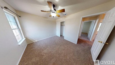 A room with a carpeted floor and a ceiling fan.
