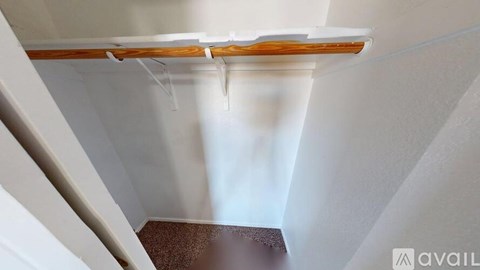 A white room with a brown floor and a white ceiling with a wooden beam.