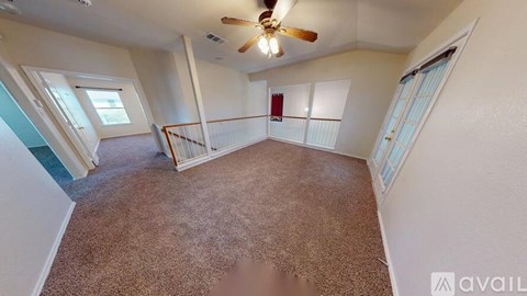 A room with a carpeted floor and a ceiling fan.