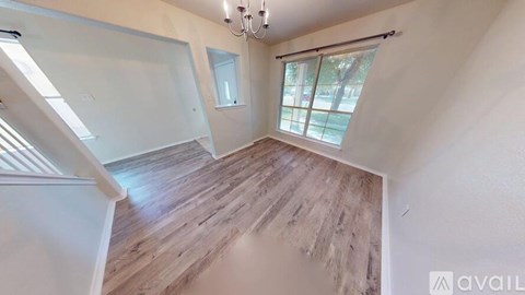 A room with wooden flooring and a window with blinds.