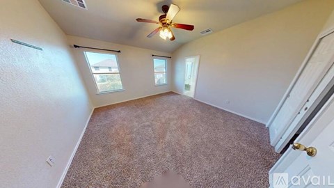 A room with a carpeted floor and a ceiling fan.