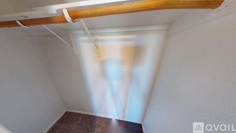 A room with a window and a wooden beam on the ceiling.