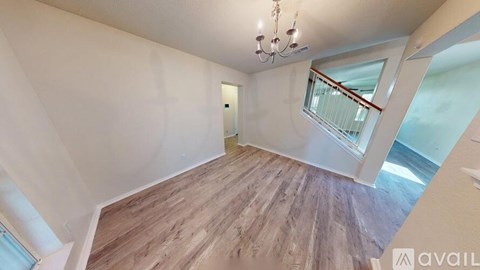 A room with wooden flooring and a chandelier.