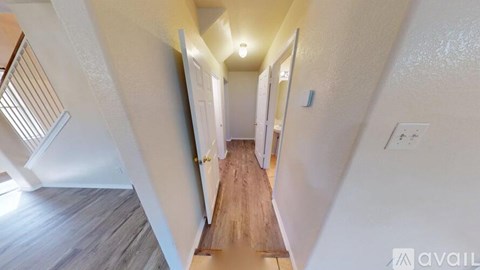 A long hallway with a wooden floor and white walls.