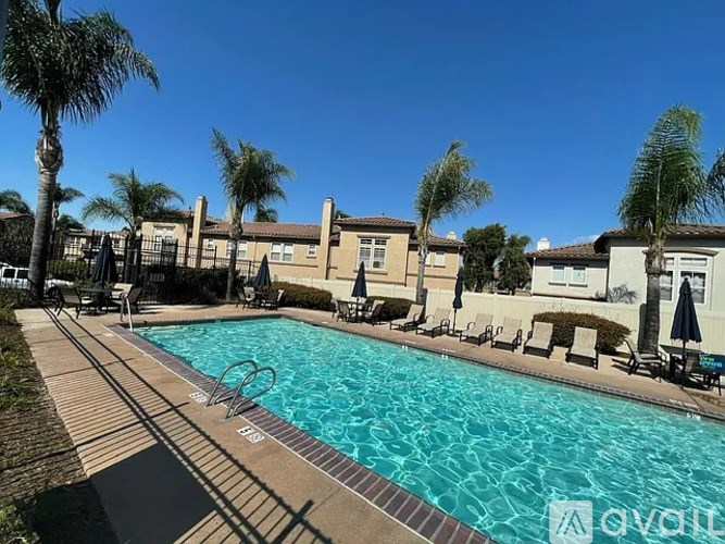A swimming pool surrounded by palm trees and lounge chairs.