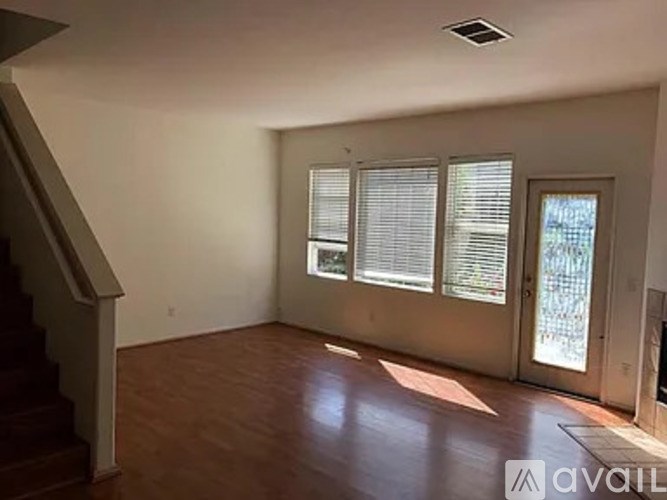 A room with wooden floors and a staircase on the left side.