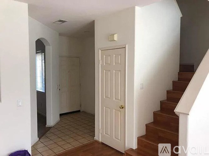 A hallway with a white door and a staircase.