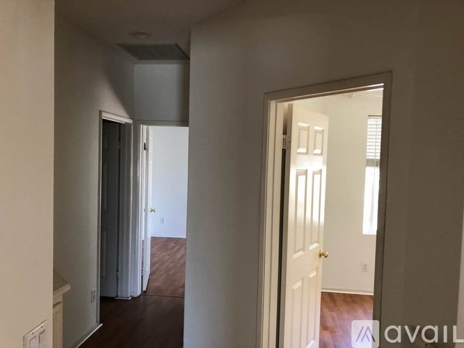 A hallway with a white door and a white wall.