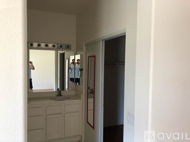 A bathroom with a sink, mirror and a man in the mirror.