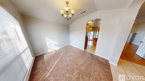 A room with a brown carpet and a chandelier.