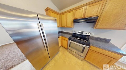 A kitchen with wooden cabinets and a stainless steel refrigerator.