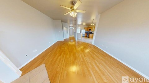A spacious room with wooden flooring and a ceiling fan.