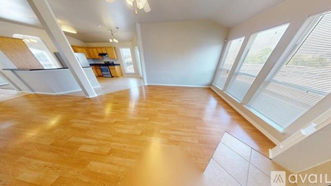 A spacious room with wooden flooring and large windows.