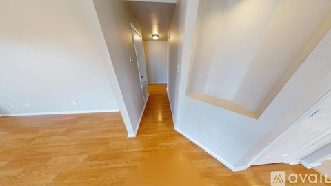 A hallway with wooden floors and white walls.