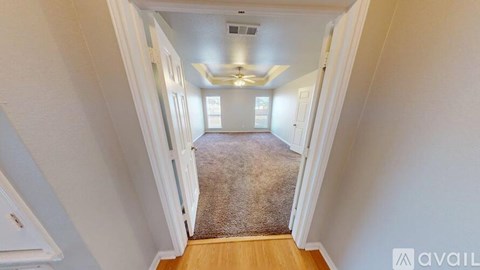 A hallway with a carpeted floor and white walls leading to a door.