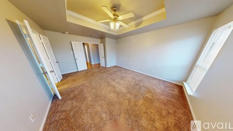 A room with a brown carpet and a ceiling fan.