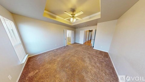 A room with a carpeted floor and a ceiling fan.