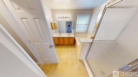 A bathroom with a glass shower door and a wooden vanity.