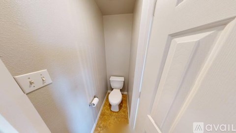 A white toilet in a small bathroom with a white door.