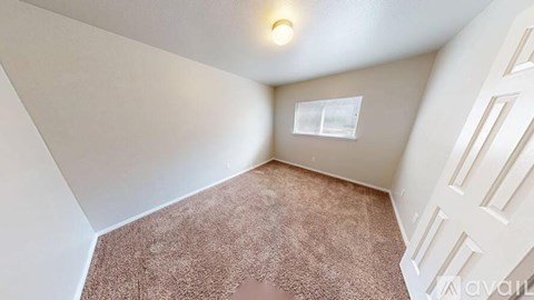 A room with a carpeted floor and a window.