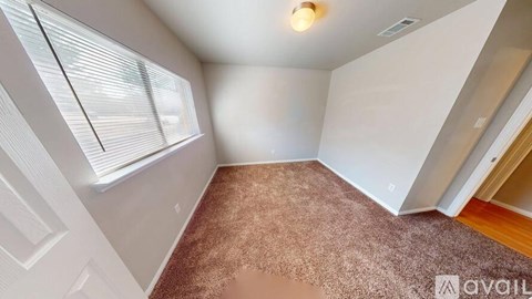 A room with a brown carpet and a window with blinds.