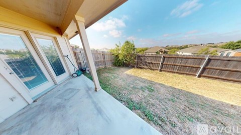 A patio with a concrete floor and a view of a fence and trees.
