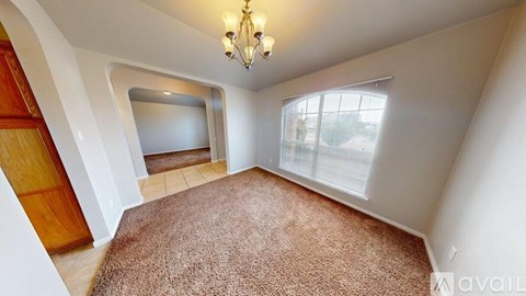 A room with a brown carpet and a chandelier.
