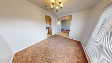 A room with a brown carpet and a chandelier.