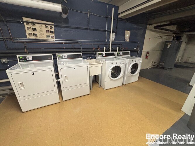 A row of washing machines are lined up in a laundry room.