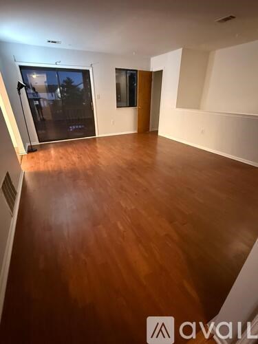 A room with wooden flooring and a sliding glass door.