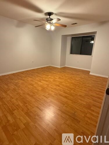 A room with wooden flooring and a ceiling fan.