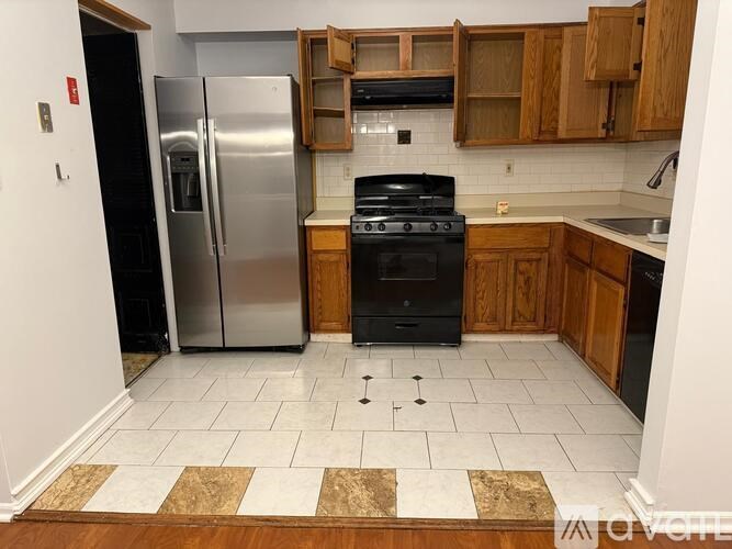 A kitchen with a black stove top oven and a silver refrigerator.