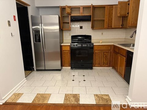 A kitchen with a black stove top oven and a silver refrigerator.