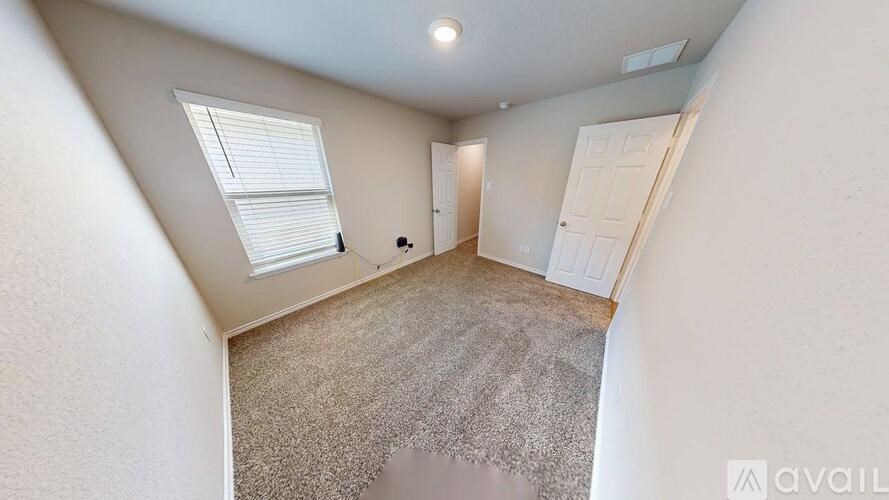 A room with a carpeted floor and a window with blinds.