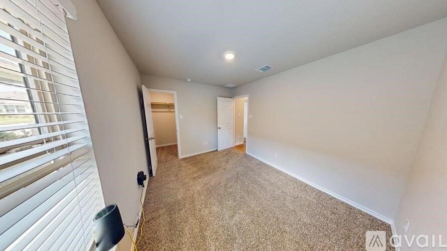 A room with a carpeted floor and a window with blinds.