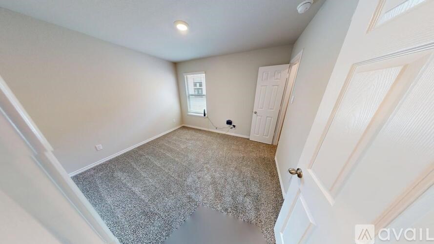 A room with a carpeted floor and a door on the right side.