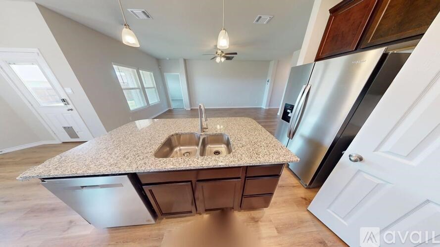 A kitchen with a granite countertop and stainless steel appliances is available for rent.