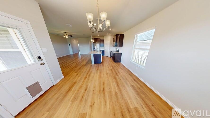 A spacious room with wooden flooring and a chandelier hanging from the ceiling.