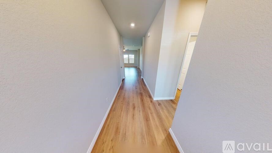 A long hallway with wooden floors and white walls.