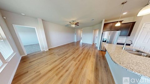 A spacious room with wooden flooring and a kitchen area with a sink and stove.