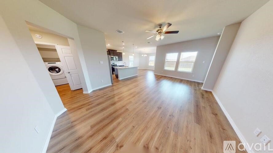 A spacious room with wooden flooring and a ceiling fan.