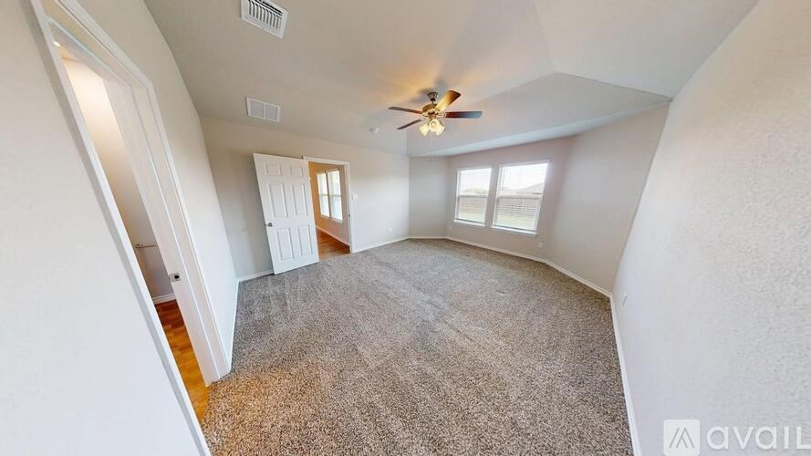 A room with a ceiling fan and carpeted floor.