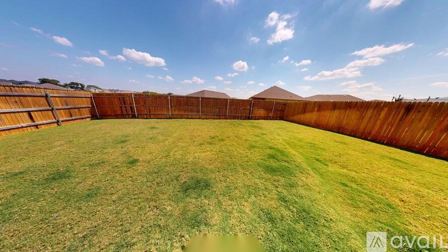A backyard with a wooden fence and a grassy field.