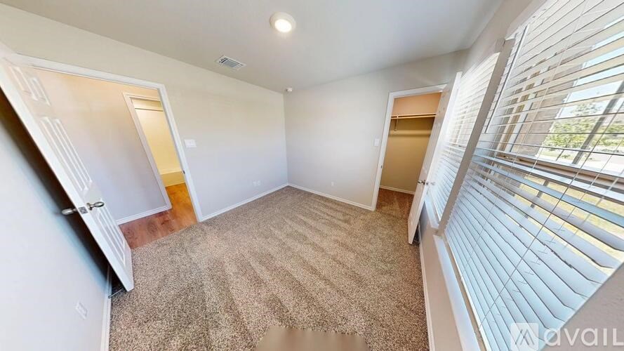A room with a carpeted floor and a window with blinds.